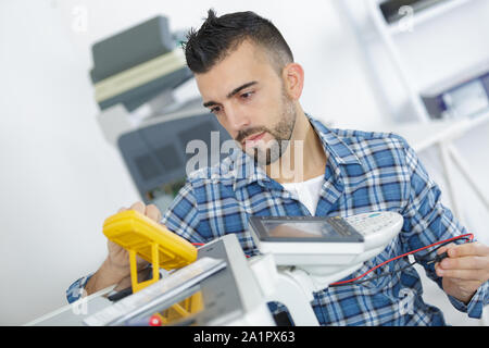technician testing phoocopier using multimeter Stock Photo