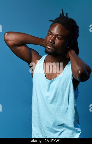 handsome sleepy tired man waking up in the morning, stretching , close up portrait, isolated blue background, studio shot Stock Photo