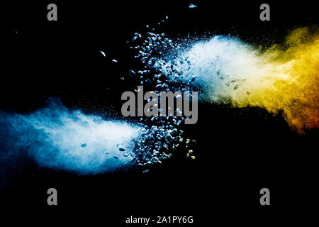 Split debris of stone exploding with blue powder against black background. Stock Photo