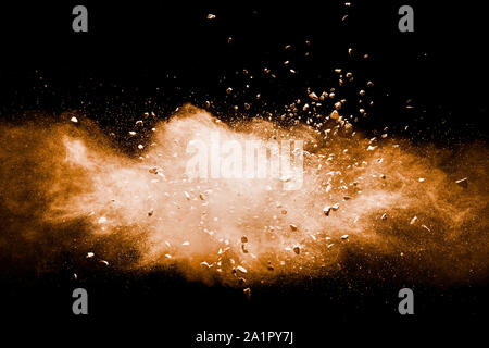Split debris of stone exploding with orange powder against black background. Stock Photo