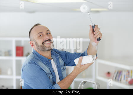 happy man installing a spotlight in the room Stock Photo