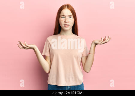confused girl raising her palms, cannot believe in news, Really Are you kidding close up portrait, isolated pink background, studio shot Stock Photo