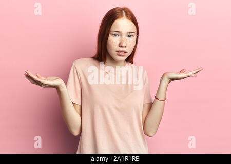 serious woman shrugs her shoulders, student doesn't know how to pass exams. close up portrait, isolated pink background, studio shot. Stock Photo