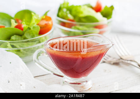 Citrus salad dressing made of blood oranges in small glass pitcher on rustic wooden table Stock Photo