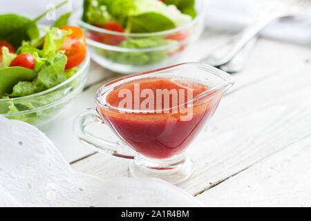 Citrus salad dressing made of blood oranges in small glass pitcher on rustic wooden table Stock Photo