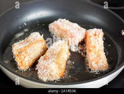 Coconut crusted salmon preparation. Salmon fillets frying in pan Stock Photo