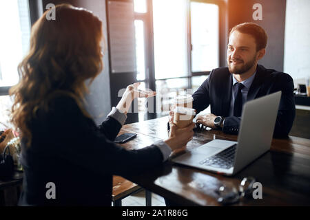 two cheerful business people having coffee break, enjoying drinking tea, pleasant conversation with a partner. Stock Photo