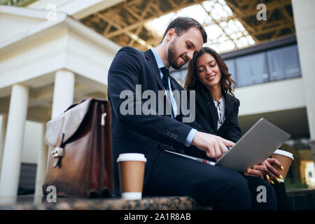 pleasant couple in fashion suits watching video, film, close up side view photo.conversation Stock Photo