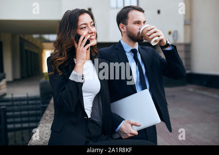 young business people have finished working on a project, woman is talking with a client, man enjoying drinking coffee. time for break Stock Photo