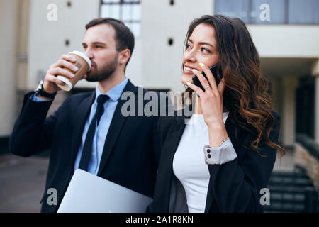 successful young business people talking with smart phone and drinking tea during coffee break. close up side view photo Stock Photo