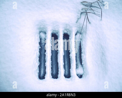 Drain spring under fresh powder snow. Water droping from the melting snow into the sewer. Stock Photo