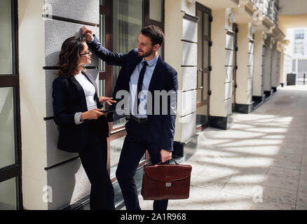 Confident handsome businessman explaining something to his beautiful female colleague while coming back from work. lifestyle, love, friendship Stock Photo