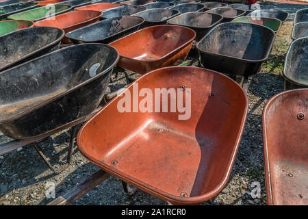 A collection of wheelbarrows parked together cleaned out and ready for use at the farm outside on a sunny day in autumn Stock Photo