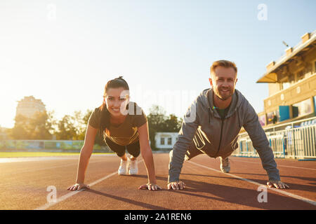 Young couple doing pushups in the stadium Stock Photo
