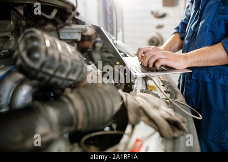 Fingers of young mobile worker of technical repair service pressing keys of laptop while trying to find out the problem Stock Photo