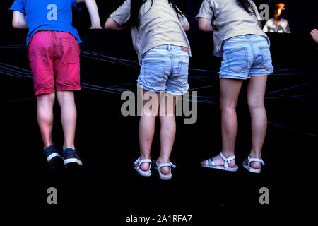 Kids clambering on to a stage to watch a performance. Stock Photo