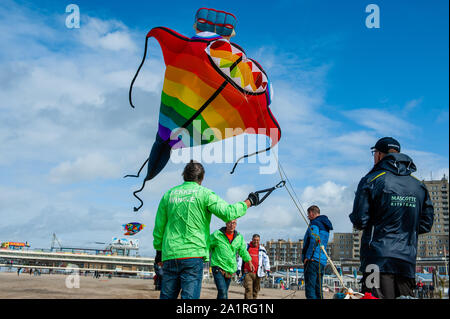 Men flying kites during festival.The international Kite Festival Scheveningen makes the most of the consistent prevailing winds blowing along The Hague's beach resort. Kite builders and enthusiasts from around the world come together to fly the fruits of their creative labour. The annual event sees the skies over the southern part of Scheveningen beach fill with giant kites of every shape and colour, flying teddy bears, elephants and fish. Visitors also get to stay up to date with the latest in kite-powered sport, from kite-surfing and kite-yachting to kite-skateboarding and kite-skiing. Unfor Stock Photo