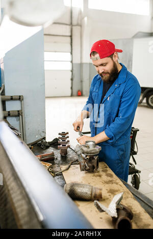 Young professional technician fixing parts of car engine together with help of handtool in workshop Stock Photo