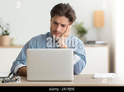 Unhappy Office Manager Sitting At Laptop Working In Office Stock Photo