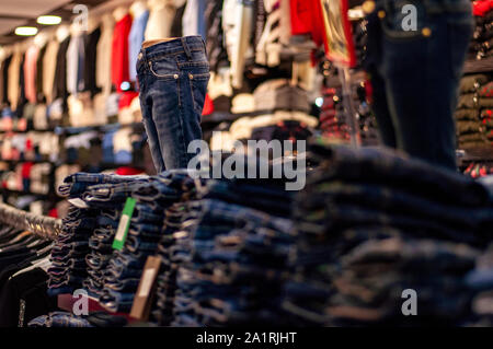 Jeans are stacked in piles in a store. Jeans are stacked on a shelf. Size range Stock Photo