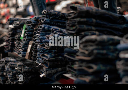 Jeans are stacked in piles in a store. Jeans are stacked on a shelf. Size range Stock Photo