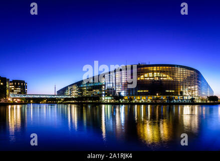 Nightfall view at blue hour of the glass facade and footbridge of the Louise Weiss building, seat of the European Parliament in Strasbourg, France. Stock Photo