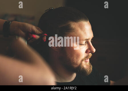 York, UK - 18th August 2019: Groom gets their hair cut and styled before getting married. Groom has beard and long hair Stock Photo