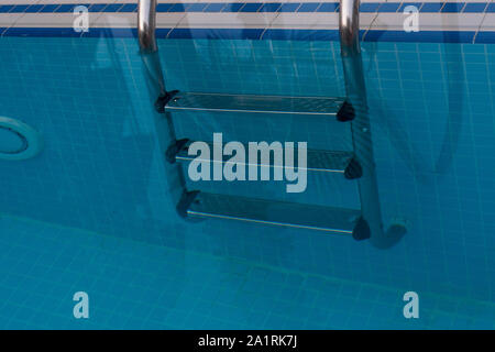 Three steps metal staircase in the water pool. Safety in the pool. The convenience of use Stock Photo