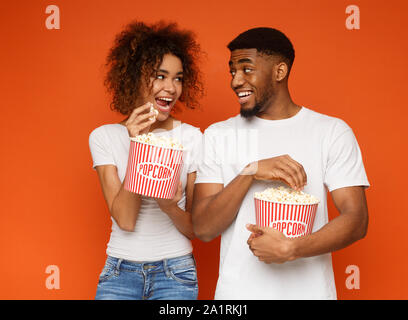 Positive african man and woman eating popcorn Stock Photo