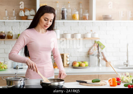 Young woman preparing meal on stove at home Stock Photo