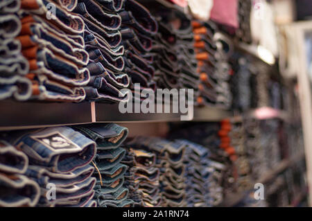 Jeans are stacked in piles in a store. Jeans are stacked on a shelf. Size range Stock Photo