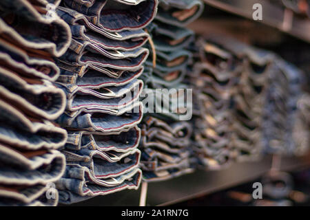 Jeans are stacked in piles in a store. Jeans are stacked on a shelf. Size range Stock Photo