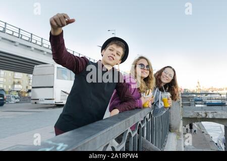 Teenagers boy and two girls with street food talking outdoor. Stock Photo