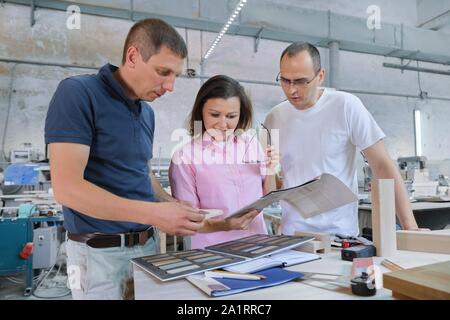 Group of working people discussing work process, wood products in carpentry workshop. Stock Photo