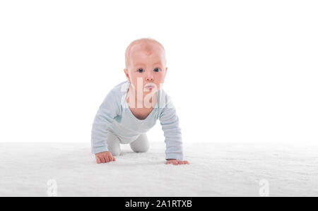 Small baby girl on a white carpet in a light room. Stock Photo