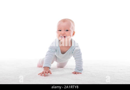 Small baby girl on a white carpet in a light room. Stock Photo