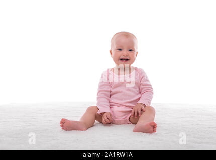 Small baby girl on a white carpet in a light room. Stock Photo