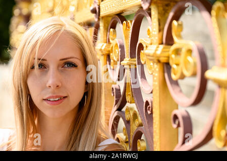 Close up portrait of an attractive young woman at the decorative gilded iron perimeter railings, surrounding the historic Albert Memorial, in Kensingt Stock Photo