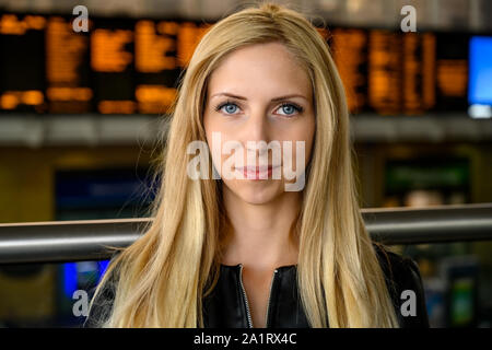 Close up portrait of an attractive smiling young woman with a train station in the background in downtown London, United Kingdom Stock Photo