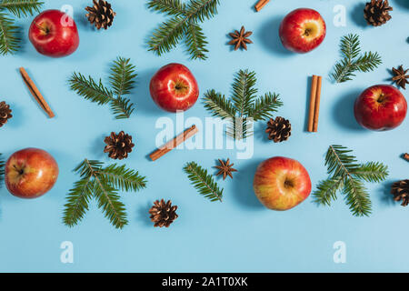 Winter composition. Frame made of fir tree branches, pine, red apple and cinnamon on pastel blue background. Autumn, fall, winter concept. Flat lay, t Stock Photo