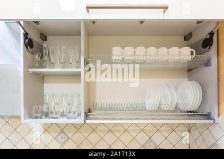 White kitchen cupboard with glasses, cups and bowls. Pastelles Stock Photo  - Alamy