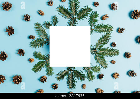 Christmas composition. Tree branches, pine, white frame, acorn on pastel blue background. Christmas, winter, new year concept. Flat lay, top view, cop Stock Photo