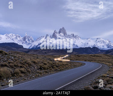 The road to el chalten with car light trails on the road and mount fitzroy and cerro torre in the background