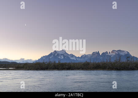 Panorama view of the Paine Massif from the rio Serrano area. Waxing crescent moon in the early evening sky. Plenty of copy space. Stock Photo