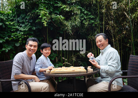 Three people playing chess between the two generations Stock Photo