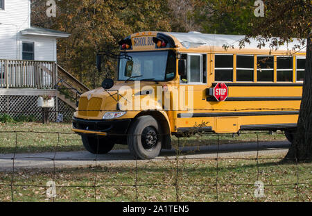 A school bus sits outside a farm house, waiting for the kids to come out and get on the bus Stock Photo