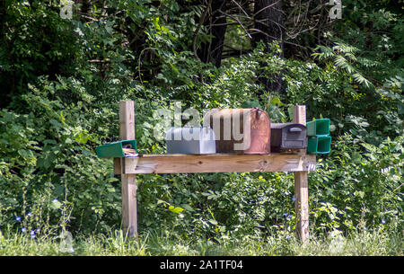 old rural mail and news paper boxes stand on the side of a rural road in Southern Michigan USA Stock Photo
