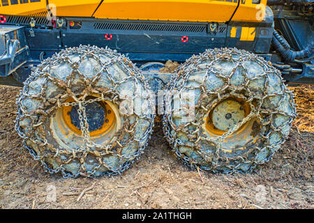 Logging machine wheels equipped with chains working in the forest Stock Photo