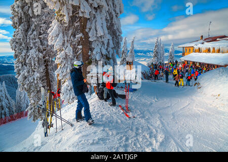 Group of sporty skiers relaxing and enjoying the view. Skiers relaxing at terrace of mountain restaurant and cafe chalet, Poiana Brasov ski resort, Ca Stock Photo