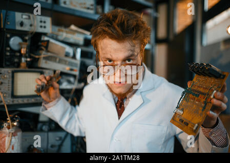 Strange engineer holds electric tube in laboratory Stock Photo